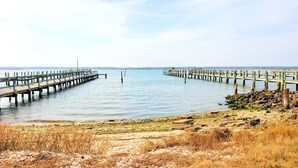A long wooden pier extending into calm water, with a rocky shoreline in the foreground. - Miss Agnes - Water Front 3BR home PET FRIENDLY, NO LINENS PROVIDED (Chincoteague)