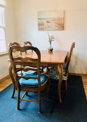 Un comedor con una mesa y sillas de madera, un florero con flores y un cuadro en la pared.