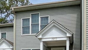 A two-story house with a red front porch and white railings.