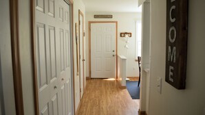 A hallway with wooden flooring, white doors, and a welcome sign.