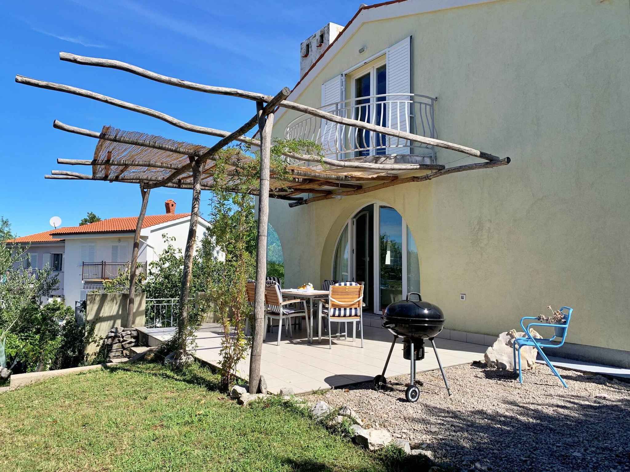 A patio with a grill, outdoor furniture, and a pergola.