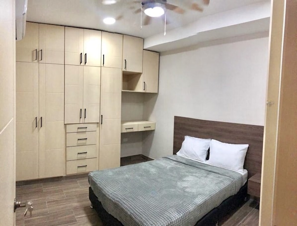 Un dormitorio con cama, armario y ventilador de techo.