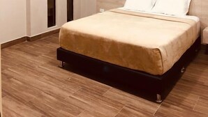 Un dormitorio moderno con cama, suelo de madera, ventilador de techo y armario empotrado.