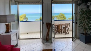 A room with a view of the sea, a balcony with a table and chairs, and a potted plant. - --SunRise-- (Montesilvano)