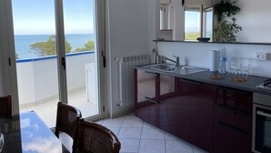 A modern kitchen with a view of the sea, a dining area with a glass table, and a balcony with a view. - --SunRise-- (Montesilvano)