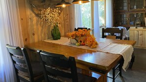 Una mesa de comedor de madera con sillas, un reloj y un florero con flores.
