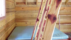 A wooden cabin interior with a bed, a window, and a wooden ladder. - Shady Pine Primitive Cabin 2 @Spring Lake Ranch (Potosi)