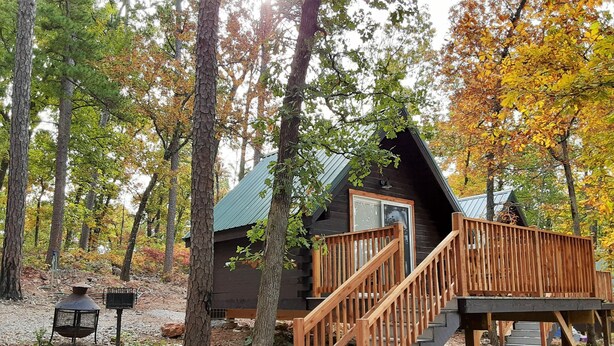 A cabin with a wooden staircase leading to a deck, surrounded by trees with autumn foliage. - Shady Pine Primitive Cabin 2 @Spring Lake Ranch (Potosi)