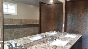 A bathroom with a large mirror, two sinks, and a wooden door. - Shady Pine Primitive Cabin 2 @Spring Lake Ranch (Potosi)