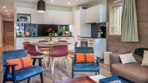 Una cocina moderna con armarios blancos, un microondas y un comedor con sillas rojas y azules.
