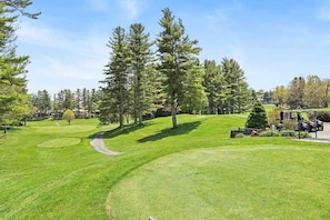 A golf course with a well-maintained fairway, a putting green, and a clubhouse.