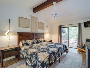 Una camera da letto con un letto grande, una scrivania, una sedia e una ventola a soffitto.