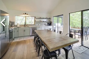 A modern kitchen with a dining area, large windows, and a view of the outdoors.