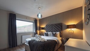 A modern bedroom with a bed, bedside lamps, a window, and a view of the outdoors. - Hot tub lodge with stunning view (Taynuilt)