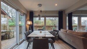 A dining area with a large table, chairs, and a sofa. - Hot tub lodge with stunning view (Taynuilt)
