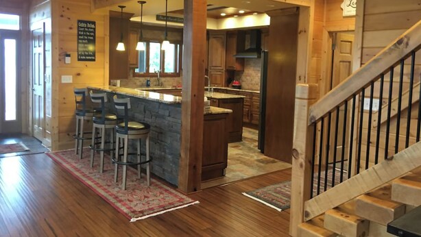 A wooden interior with a kitchen, bar area, and a staircase. - 360 Mountain Top Views! Private Pool, Gated, Theatre, Pinball, Outdoor Kitchen! (Sevierville)