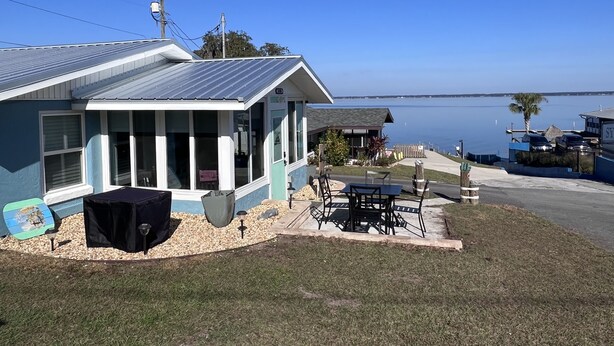 A house with a covered patio, a small deck, and a view of the water. - View of Lake Weir & private beach access  (Weirsdale)