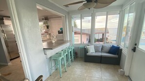 A spacious living area with a kitchen, a dining area with bar stools, a seating area with a sofa and cushions, and a ceiling fan. - View of Lake Weir & private beach access  (Weirsdale)