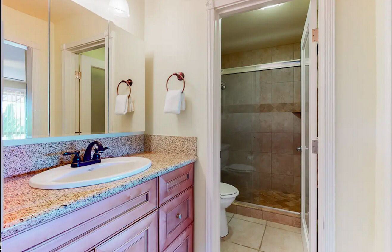 Un bagno con lavandino, specchio e doccia.