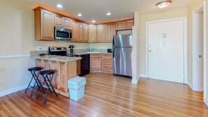 A modern kitchen with wooden cabinets, stainless steel appliances, and a wooden floor. - Palm Desert Condo. Near Tennis Gardens, Public Golf, Dog Park. EZ on the wallet! (Palm Desert)