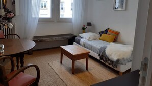 A compact living space with a sofa, a small table, a bench, and a dining table. - Cosy and bright 1-3 person apartment (caen)