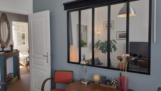 A dining area with a round wooden table, two chairs, a large mirror, and a globe on the table. - Cosy and bright 1-3 person apartment (caen)