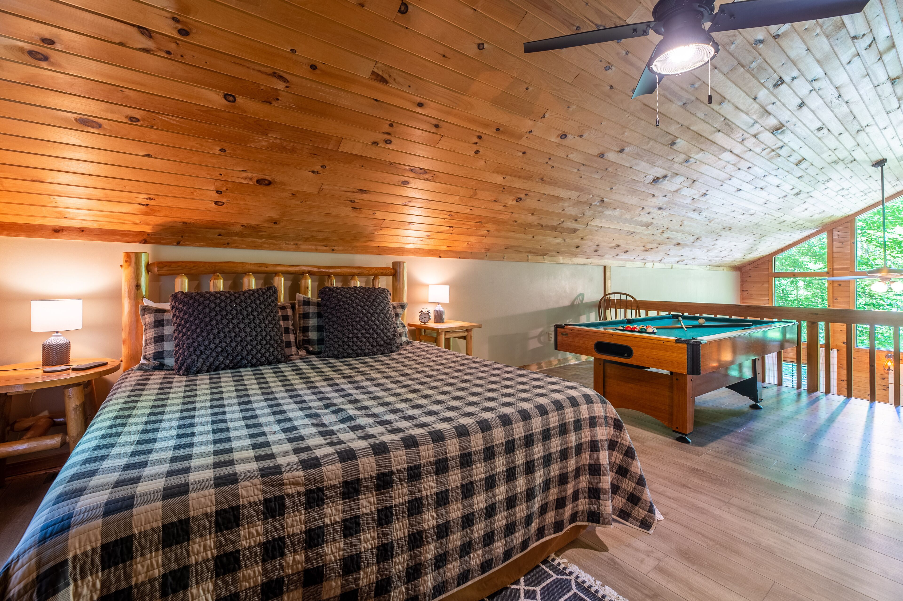Ein gemütliches Zimmer mit kariertem Bett, Billardtisch und Holzboden.