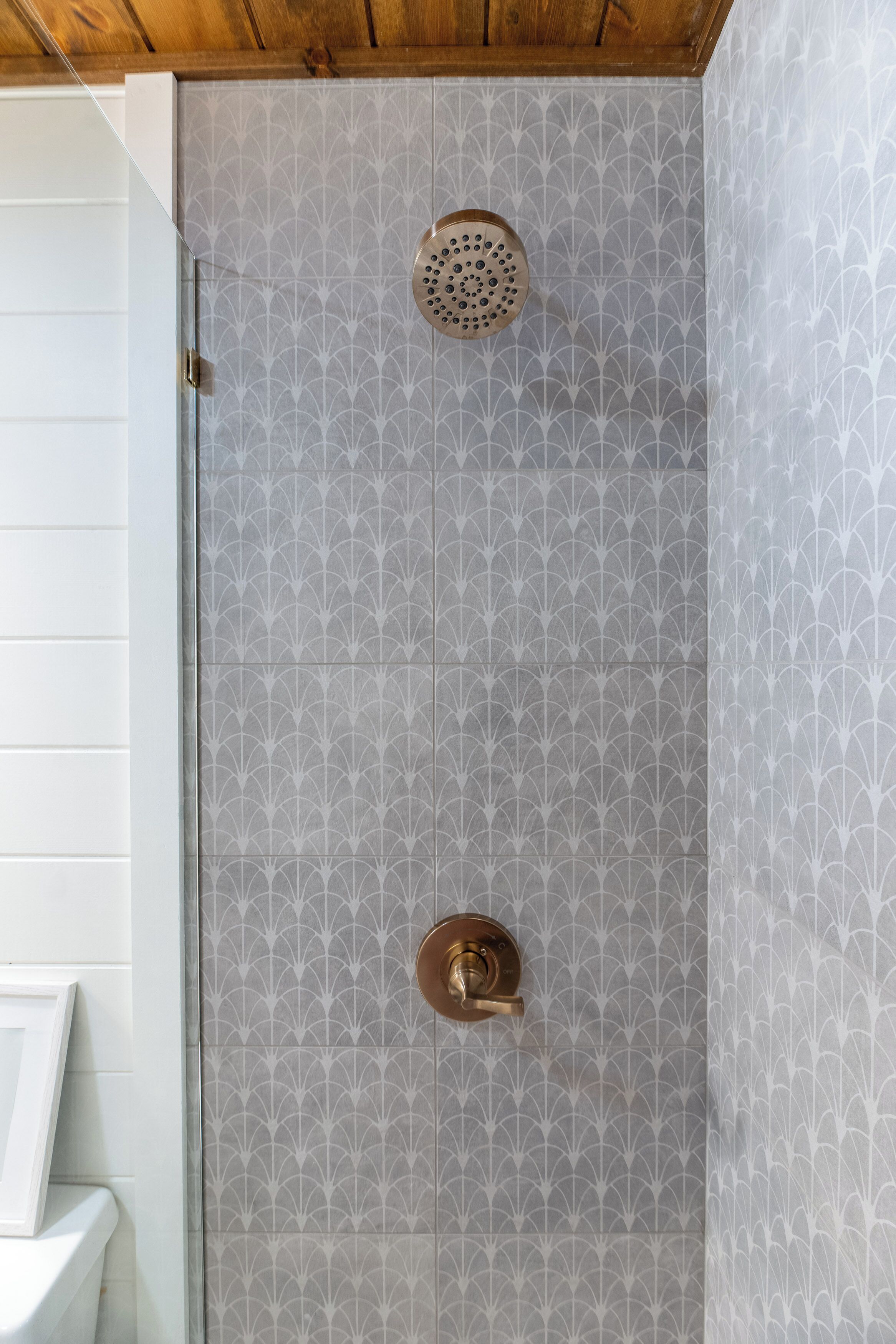 Una ducha con pared de azulejos estampados y techo de madera.