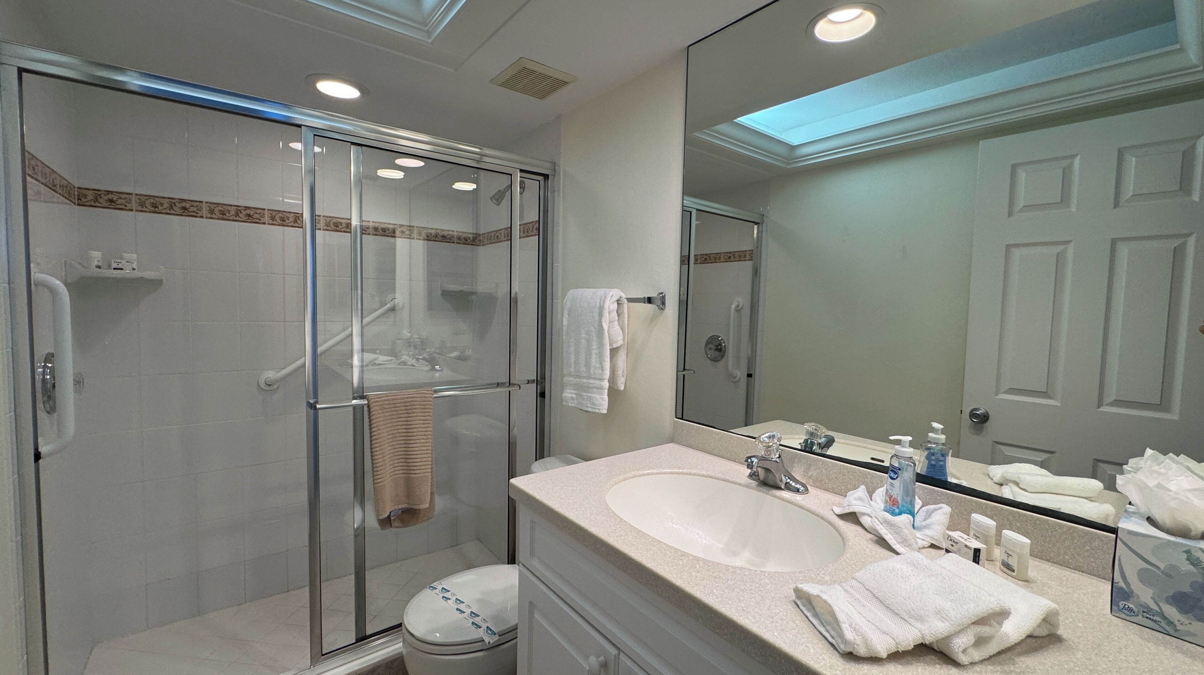 A modern bathroom with a glass-enclosed shower, a large sink, and a mirror reflecting the room.