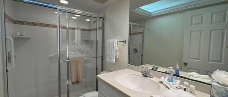 A modern bathroom with a glass-enclosed shower, a large sink, and a mirror reflecting the room.