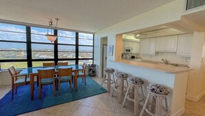 Ein Essbereich mit Blick auf die Stadt, eine Küche mit weißen Schränken und eine Bar mit Hockern.