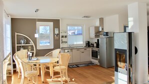 Eine moderne Küche mit Essbereich, ausgestattet mit einem runden Tisch, Korbstühlen und einem Einbauofen.