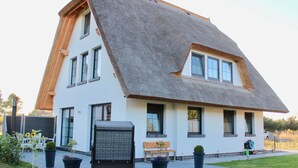 Ein modernes Haus mit steiler Satteldach, großen Fenstern und einem gepflegten Rasen.