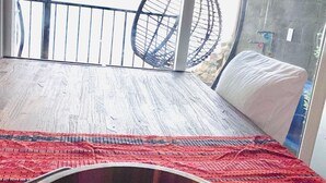 Une chambre avec un lit, un fauteuil suspendu et une vue sur l’extérieur grâce à une grande fenêtre.