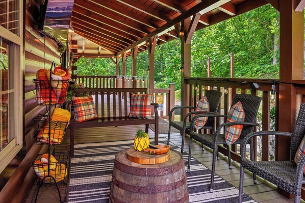 A covered porch with wicker chairs and a wooden barrel.