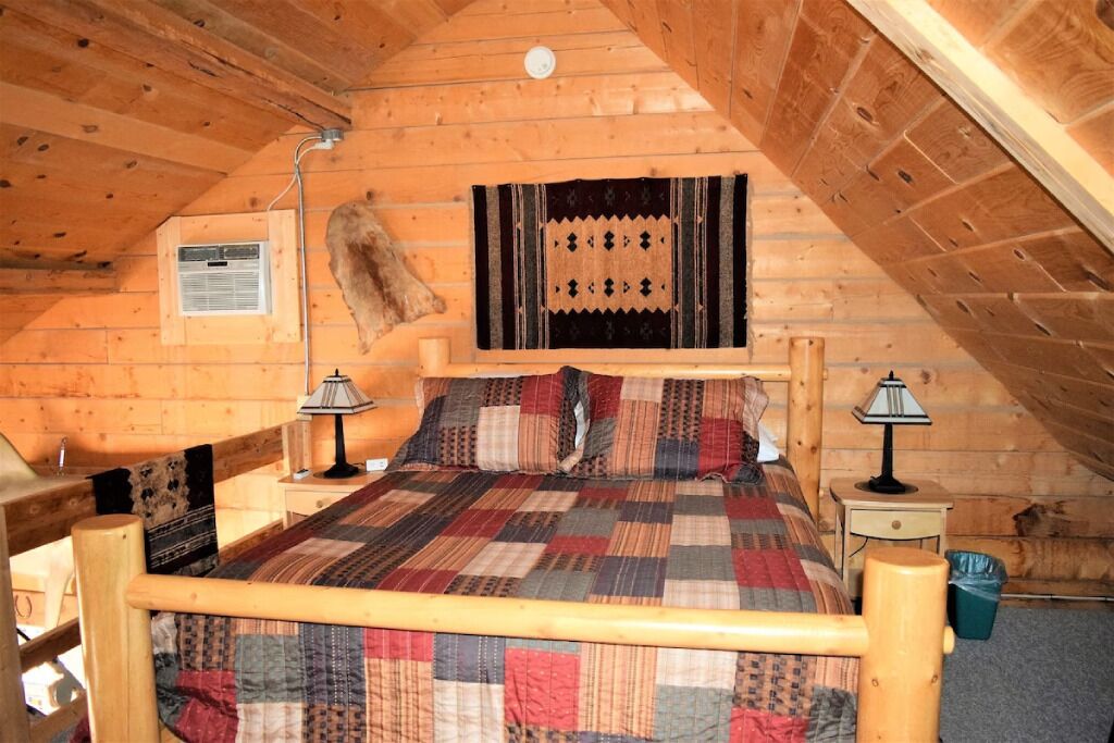 Ein gemütliches Schlafzimmer im Dachgeschoss mit einem hölzernen Bett, einer Steppdecke, einem Wandheizkörper und rustikalem Dekor.