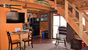 Ein rustikales Blockhaus-Interieur mit Essbereich, Küche und einer Treppe.