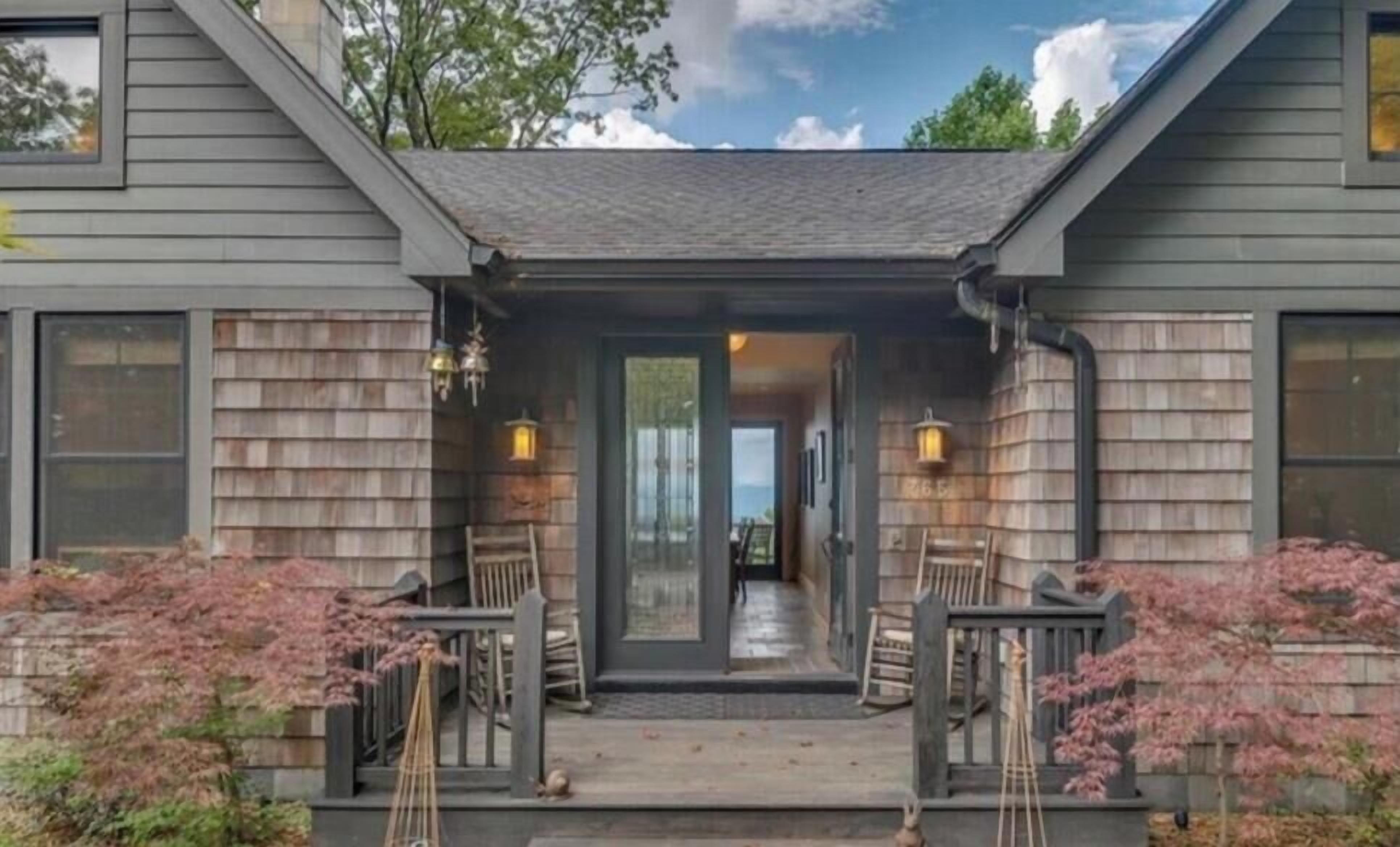 A two-story house with a covered porch, wooden siding, and a view into the interior.