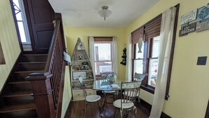 A staircase leading to a dining area with a table and chairs, a decorative shelf, and a window with curtains. - 4-bedroom a short drive to the beaches, fishing, boat, jet express to Put In Bay (Port Clinton)