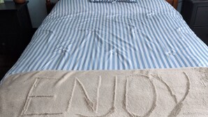 A bed with striped bedding and a blanket with 'ENJOY' embossed on it. - 4-bedroom a short drive to the beaches, fishing, boat, jet express to Put In Bay (Port Clinton)