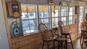 A wooden interior with a pool table, two wooden chairs, and a window with a view of a snowy landscape. - 4-bedroom a short drive to the beaches, fishing, boat, jet express to Put In Bay (Port Clinton)