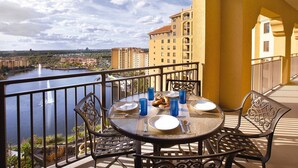 Un balcone con tavolo apparecchiato per consumare i pasti, con vista su un corpo d'acqua e edifici.