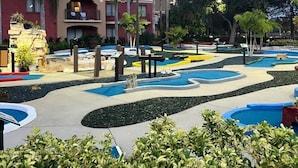 Un hotel con diverse altezze, piscine all'aperto e palme.