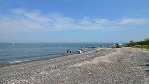 Una playa de guijarros con gente relajándose y un cielo despejado.