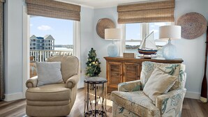 Een knusse woonkamer met uitzicht op zee, met twee fauteuils, een klein tafeltje en een decoratief model zeilboot.