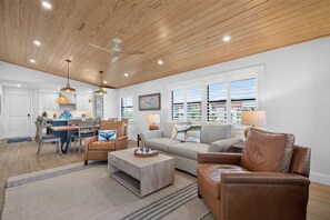 A spacious living room with a wooden ceiling, a dining area, and a kitchen.