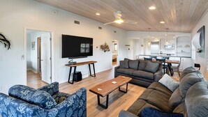 Een moderne woonkamer met een grote flatscreen-televisie, een houten salontafel en een bank.
