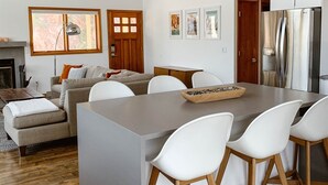A modern kitchen with a central island, white chairs, a wooden ceiling fan, and a built-in refrigerator. - Reservoir Retreat with Hot Tub and Mtn. Views! (Fort Collins)