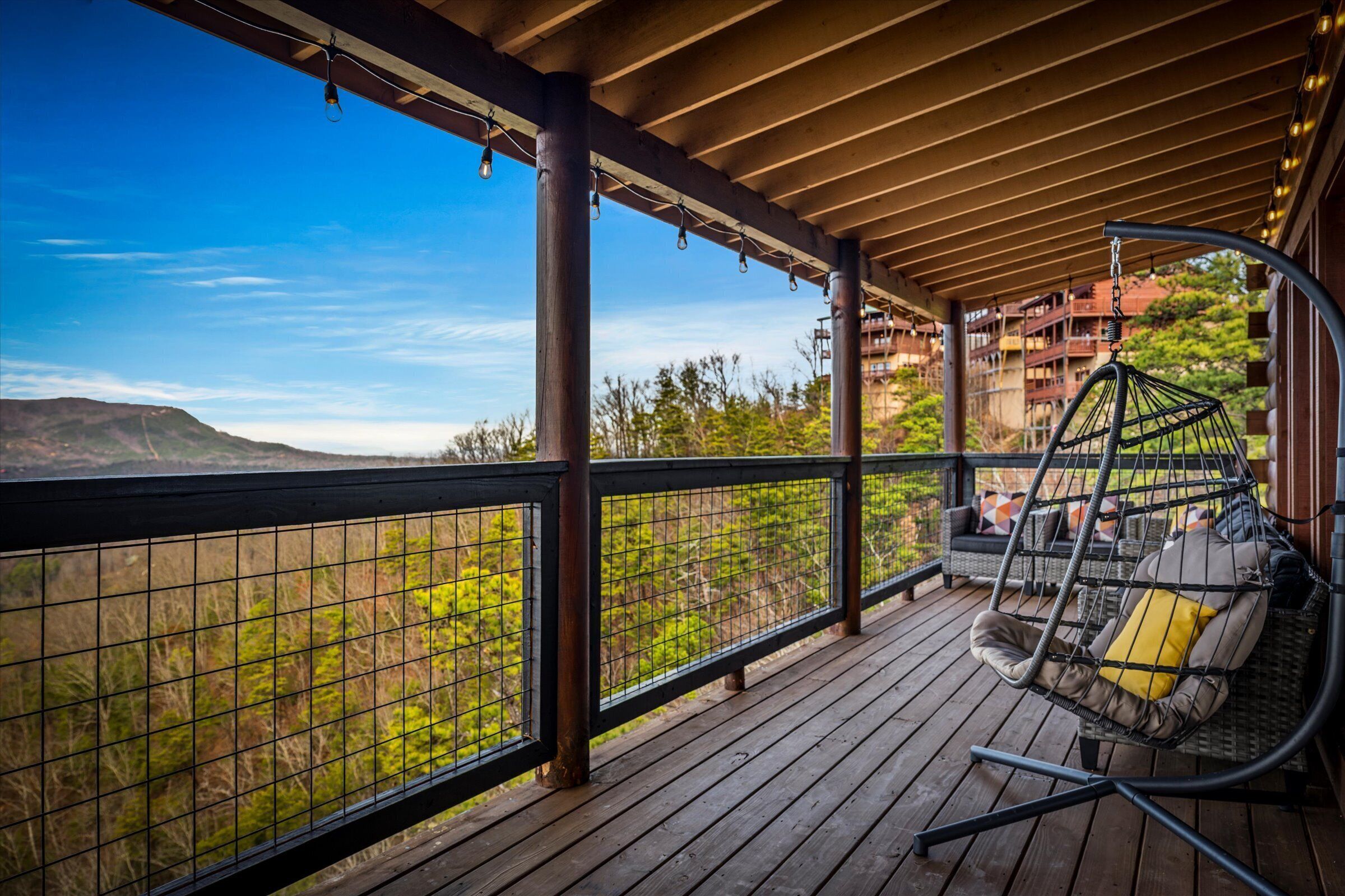 Une terrasse en bois avec un fauteuil suspendu et une vue sur un paysage montagneux.