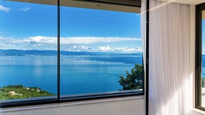 A room with a large window offering a view of a calm sea and distant mountains. - Sky Pool Villa Medveja: heated pool, spa, sea view (Medveja)